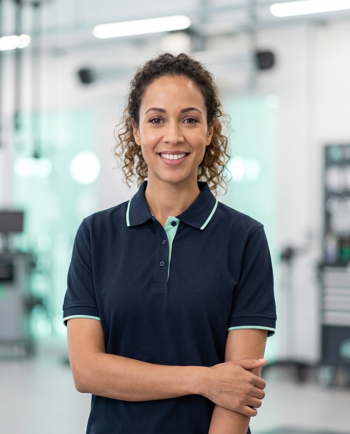 Portrait of a ClearPass smog technician in navy uniform, smiling in a bright testing bay